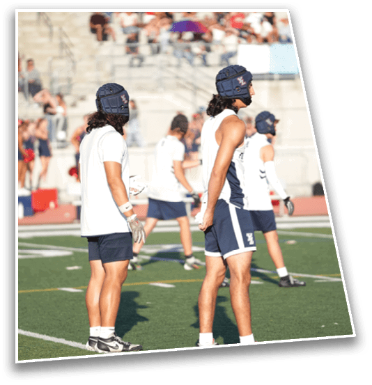 Several people wearing athletic gear and helmets stand on a sports field, appearing to prepare for or participate in a game or practice. Description generated by AI