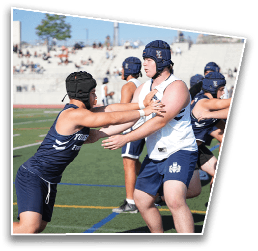 People wearing protective headgear and athletic clothing are engaged in a contact sport on a field. Description generated by AI