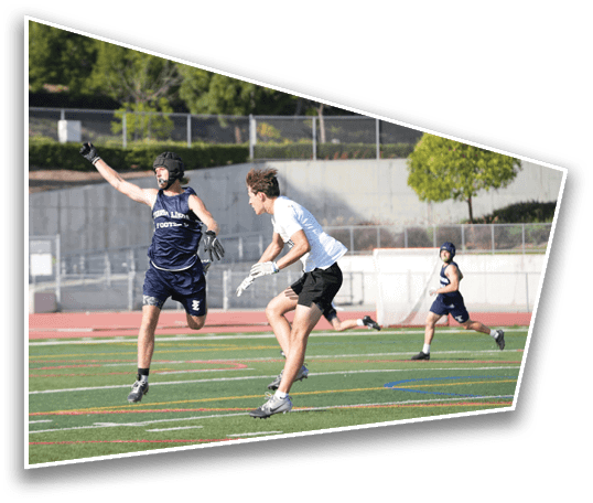 Three people wearing athletic clothing and gloves are actively playing a sport on a green field with a track and trees in the background. Description generated by AI