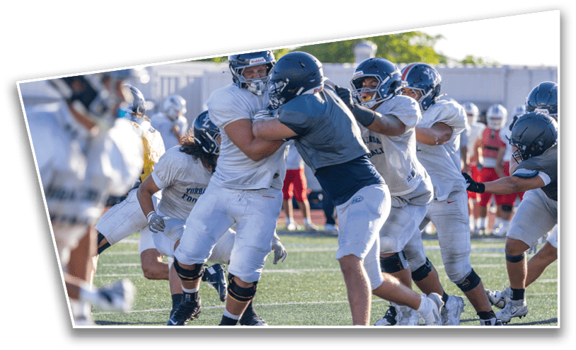 Several people wearing helmets and football uniforms are engaged in a physical play on a grassy field during a game. Description generated by AI