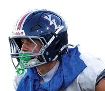 A person wearing a football helmet, gloves, and uniform is crouched in a ready position on a football field. Description generated by AI