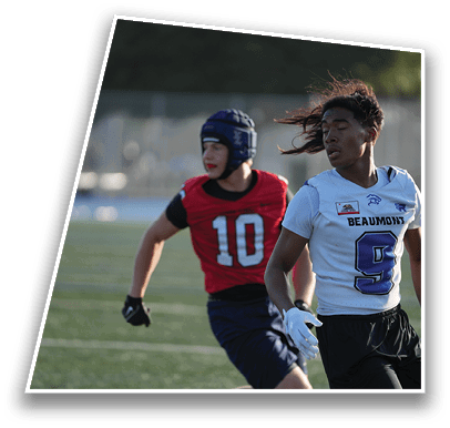 Two people wearing sports uniforms are on a field, one in a red jersey with the number 10 and a protective helmet, and the other in a white jersey with the number 9 and long hair blowing in the wind. Description generated by AI