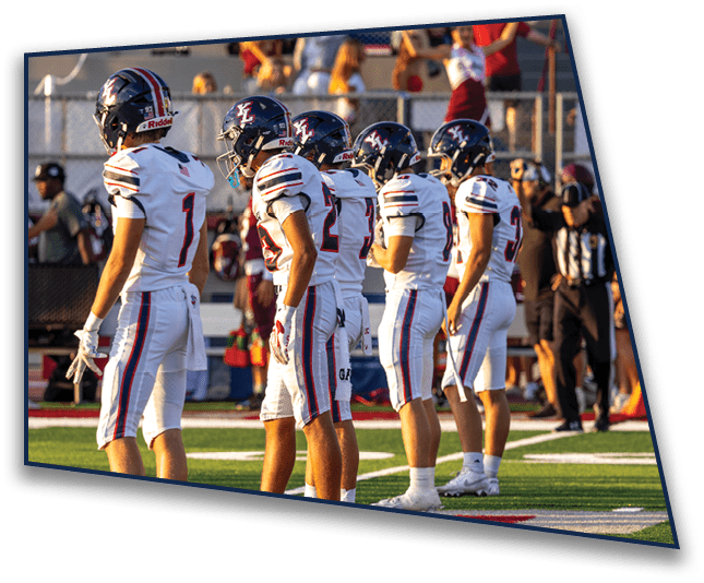 Five people in white football uniforms and helmets stand in a line on a football field during a game. Description generated by AI