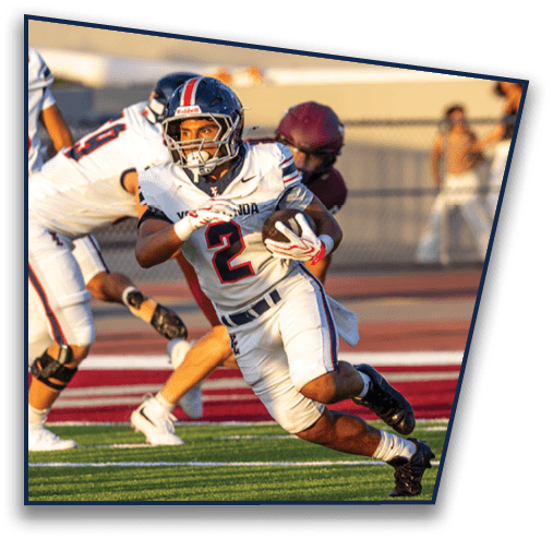 Two people wearing football helmets and uniforms are engaged in a play on a field with a blurred background. Description generated by AI
