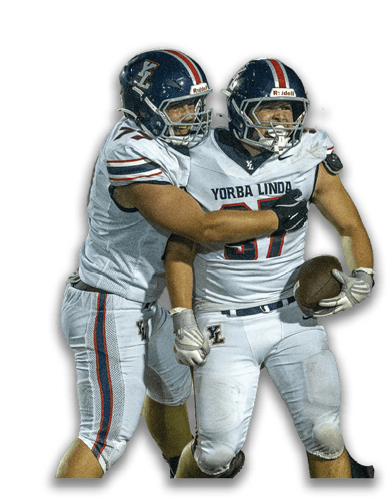 Two people in football uniforms celebrating with one holding a football and the other embracing them. Description generated by AI