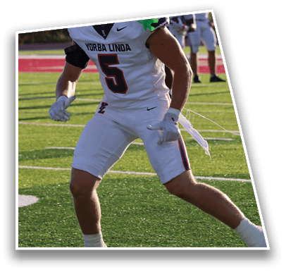 A person wearing a Yorba Linda football uniform with the number 5 is running on a football field during a game. Description generated by AI