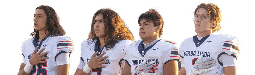 Four people wearing white football uniforms with “Yorba Linda" on the front stand side by side with their right hands over their hearts. Description generated by AI
