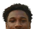 A person wearing a navy blue football jersey with the word Mustangs and the number four stands against a plain gray background. Description generated by AI