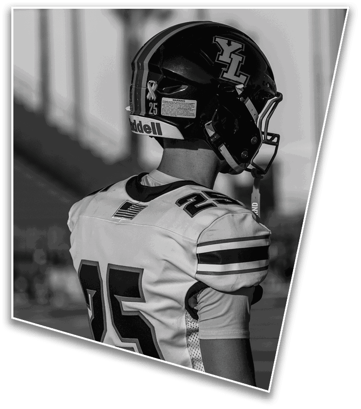 A person wearing a football helmet and jersey with the number 25 is standing on a field, facing away from the camera. Description generated by AI