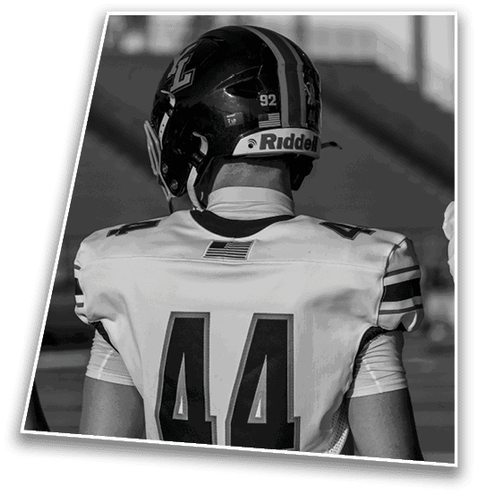 A person wearing a football helmet and jersey with the number 44 is standing on a field facing away from the camera. Description generated by AI