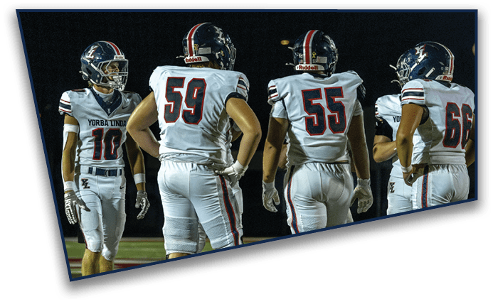People wearing white sports uniforms and knee braces stand on a football field. Description generated by AI