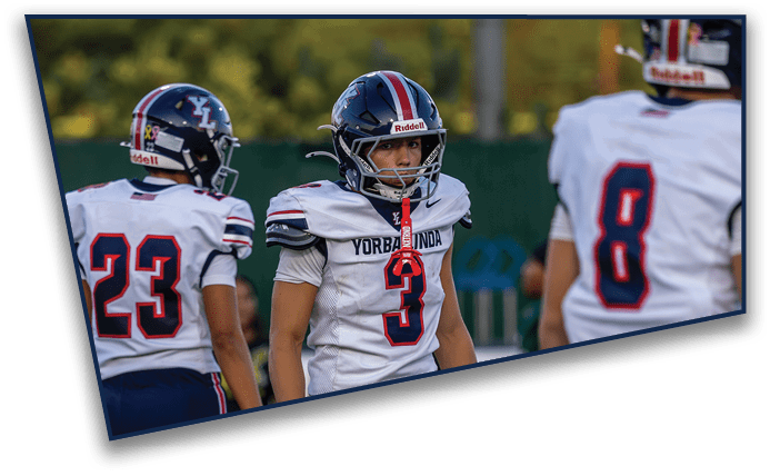 People wearing sports uniforms and cleats stand on a turf field marked with white and red lines. Description generated by AI