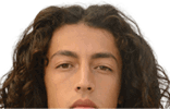 Person with long curly hair looking directly at the camera against a plain white background. Description generated by AI