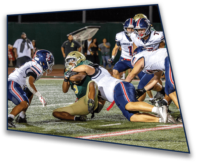 A group of football players in helmets and uniforms are engaged in a tackle on a field during a game. Description generated by AI