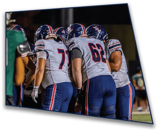 People wearing football uniforms with blue pants and white jerseys are standing together on a field. Description generated by AI