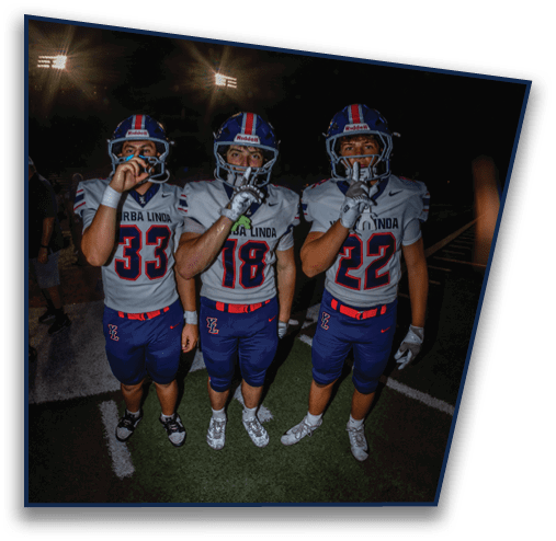 Three people wearing blue helmets with red and white stripes are partially visible at the bottom of the image against a dark background with bright lights and a faint rainbow arc above them. Description generated by AI