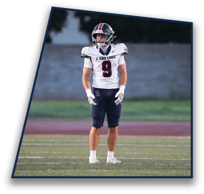A person wearing a football uniform with the number nine stands on a grassy field with a blurred background. Description generated by AI