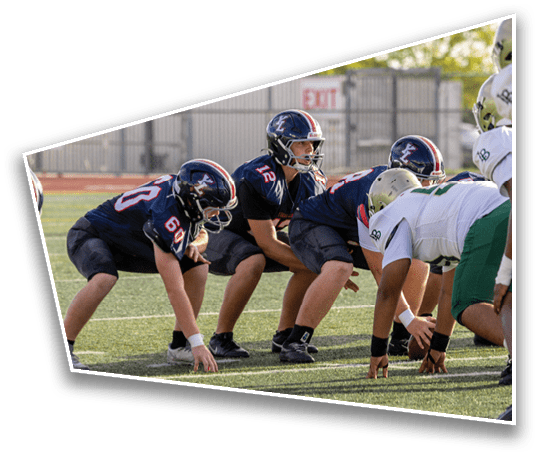 A group of people wearing football helmets and uniforms are positioned on a field, preparing for a play during a game. Description generated by AI