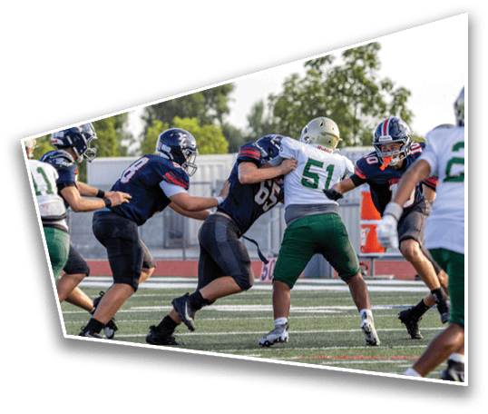 People wearing football uniforms are engaged in a play on a field with green turf and white yard lines. Description generated by AI