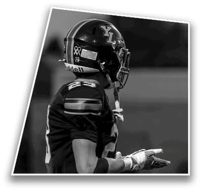 A person wearing a football uniform and helmet is standing with one hand extended as if gesturing or explaining something. Description generated by AI
