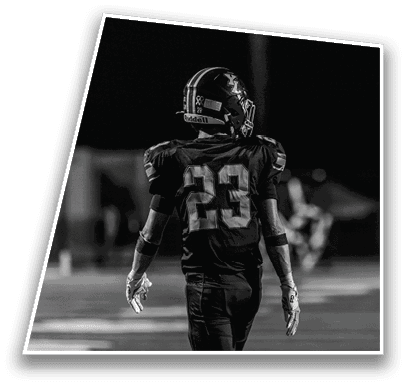A person wearing a football uniform with the number 23 on the back is standing on a field at night. Description generated by AI