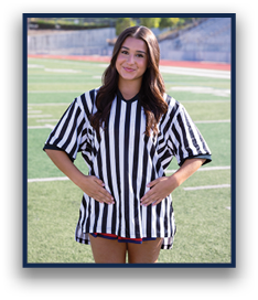 A person with long hair wearing a black and white striped referee shirt stands on a sports field with hands resting on their stomach. Description generated by AI