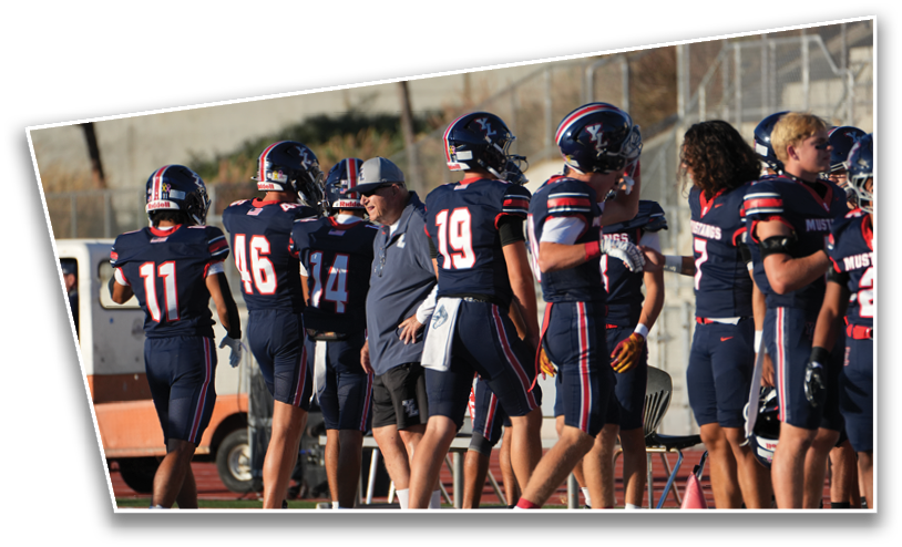 A group of people wearing football uniforms and helmets stand together on a field with a coach in casual sportswear. Description generated by AI