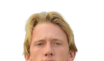 A person with medium-length blond hair is looking directly at the camera against a plain white background. Description generated by AI