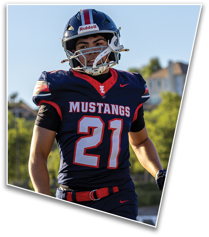 A person wearing a navy blue football uniform with the number 21 and the word Mustangs on the front is standing outdoors with a helmet on. Description generated by AI