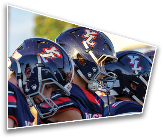 Three people wearing dark blue football helmets and matching jerseys are standing closely together, appearing focused and ready for a game. Description generated by AI