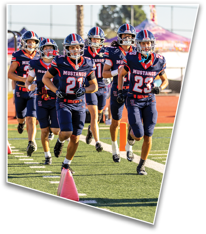 A group of people wearing navy blue football uniforms with “Mustangs" on the front are running together on a sports field. Description generated by AI