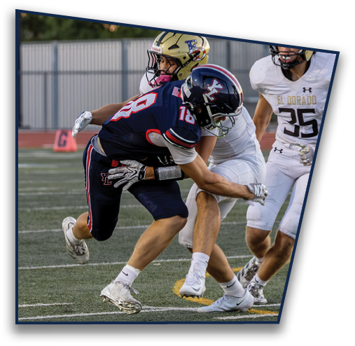 Two people in football uniforms are engaged in a tackle on a field with another player nearby. Description generated by AI