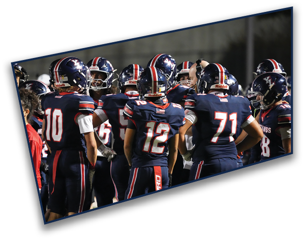 A group of people wearing dark blue football uniforms with red and white stripes are huddled together on a field. Description generated by AI