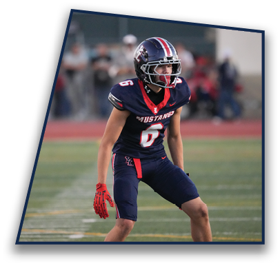 A person wearing a football uniform and helmet with the number 6 and the word Mustangs is standing on a field, appearing focused and ready for action. Description generated by AI