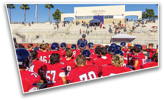 A stadium with scattered people sitting and walking on the bleachers under a clear blue sky with palm trees nearby. Description generated by AI