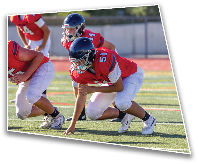 Two people in athletic clothing are crouched on a sports field, poised to start running. Description generated by AI