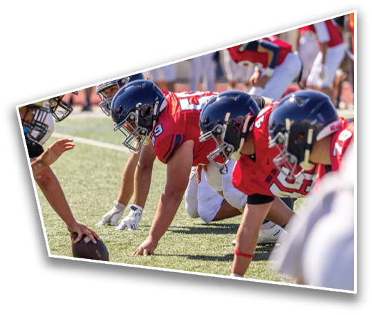 A group of people wearing football helmets and uniforms stand closely together in a line, facing the same direction. Description generated by AI