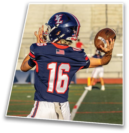A person wearing a blue football uniform with the number 16 is preparing to throw a football on a field with blurred spectators in the background. Description generated by AI