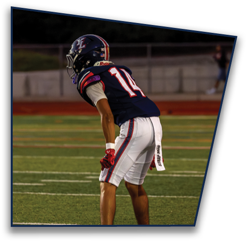 A person wearing a football uniform with the number 10 is standing on a field in a ready position. Description generated by AI