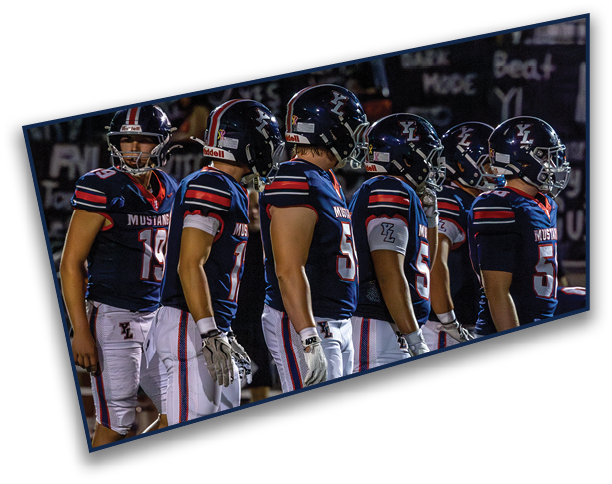 A crowd of people is sitting in bleachers at a nighttime event with some holding signs, and several individuals wearing helmets are visible at the bottom. Description generated by AI