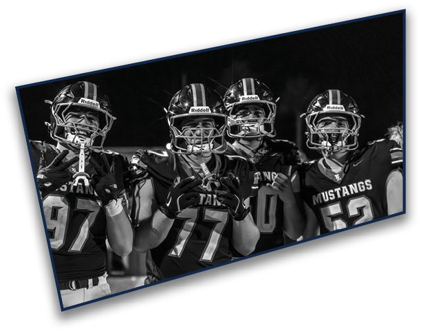 A group of people wearing dark blue football uniforms with red and white stripes are huddled together on a field. Description generated by AI