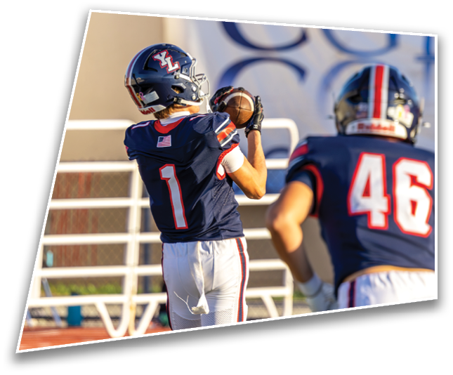 A person wearing a dark football uniform and helmet is catching a football during a game or practice. Description generated by AI