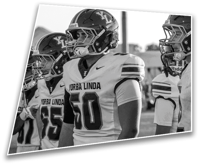Three people wearing football helmets and Yorba Linda jerseys stand side by side, looking forward. Description generated by AI