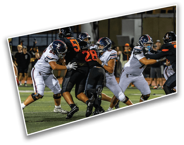 Several people in football uniforms are engaged in a play on a field with some players blocking and others attempting to advance. Description generated by AI