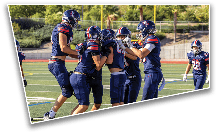 Five people in football uniforms and helmets are celebrating together on a football field. Description generated by AI