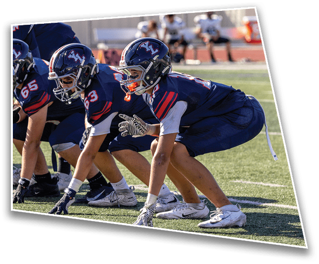 Several people wearing athletic shoes and gloves are positioned in a crouched stance on a grassy field, appearing ready to start a race or engage in a sports drill. Description generated by AI