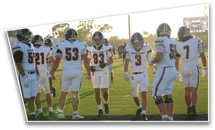 A group of people wearing white football uniforms with helmets stand together on a grassy field during sunset. Description generated by AI
