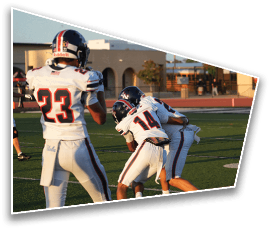 Two people in football uniforms are engaged in a tackle on a football field while another person in uniform stands nearby. Description generated by AI