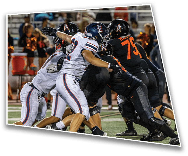 Several people in football uniforms are engaged in a close physical play on a field during a game. Description generated by AI