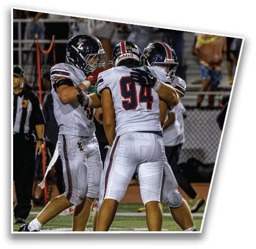 Three football players in white uniforms are celebrating on the field during a game while a referee stands nearby. Description generated by AI